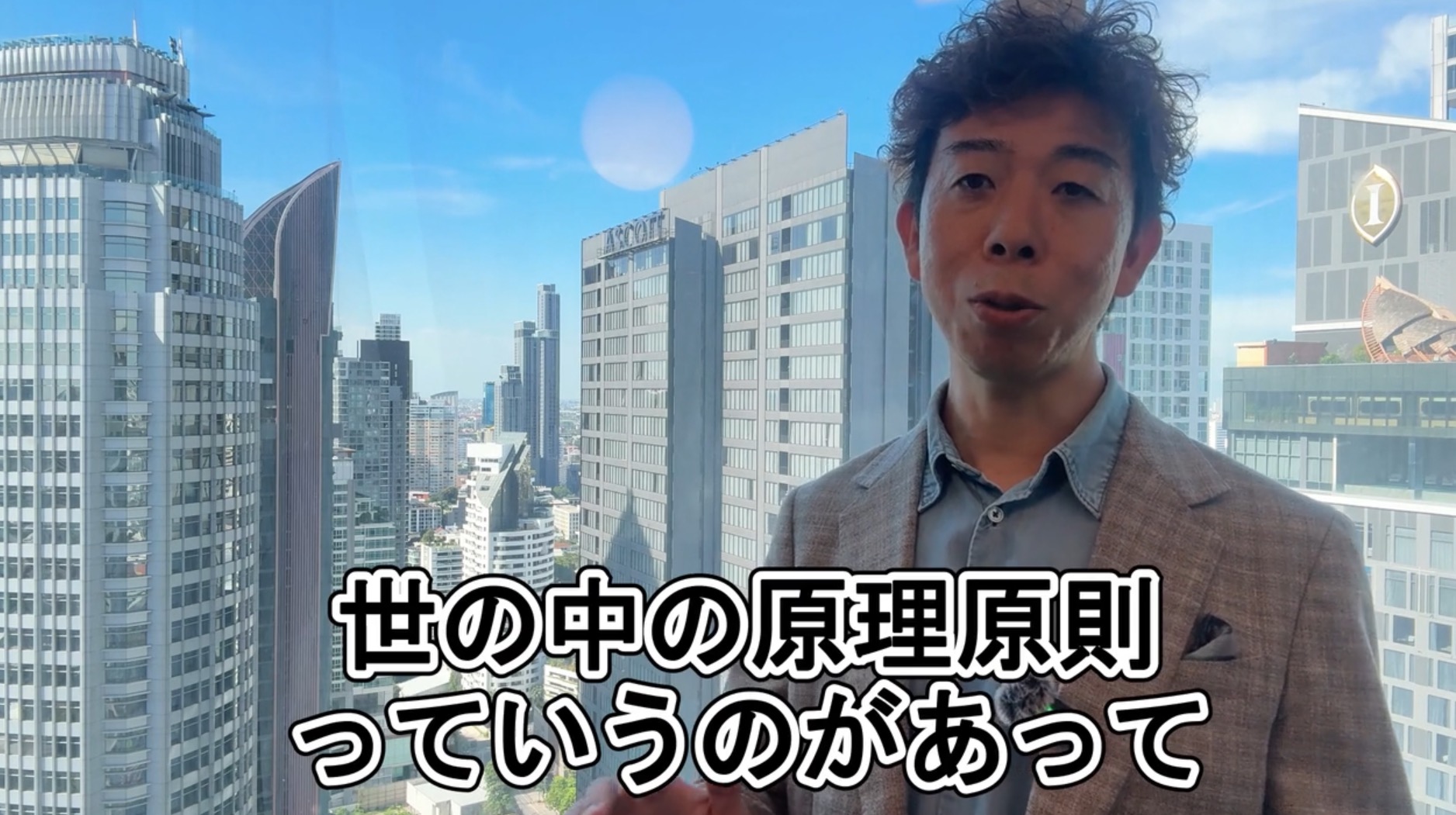 バンコクの街を背に、世の中の原理原則を説明する佐藤大介