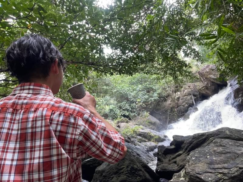 カオヤイ国立公園の滝を眺めながらコーヒーを飲む佐藤大介
