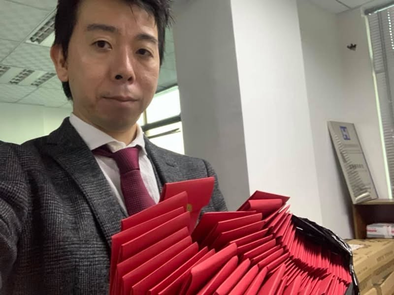 社員へ手渡す春節ボーナスの紅包を持つ佐藤大介