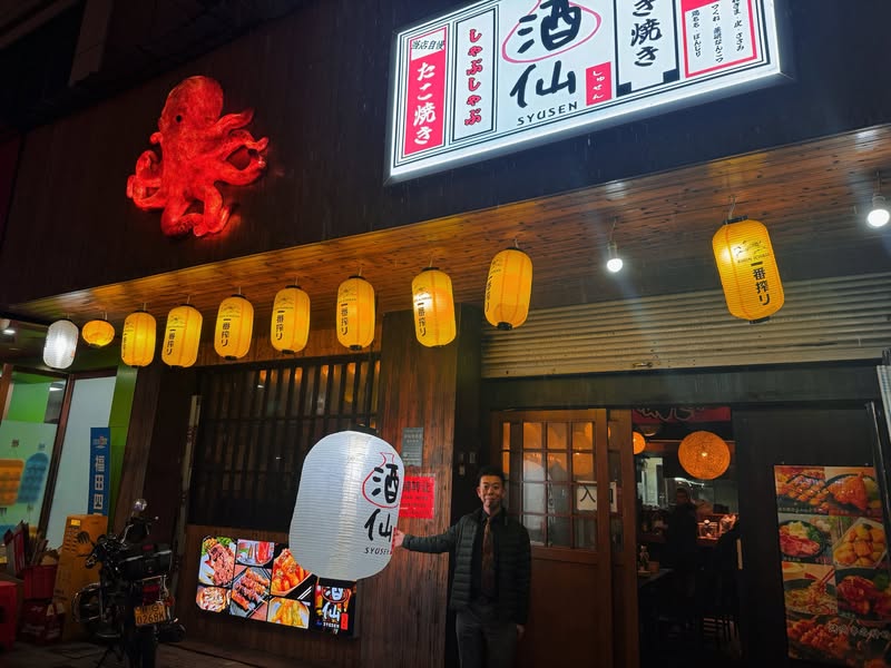義烏の居酒屋酒仙の前に立つ佐藤大介