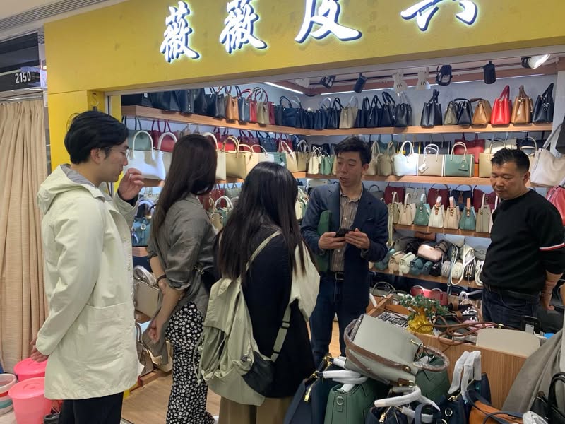 広州のバッグ問屋で参加者と商品を確認する佐藤大介