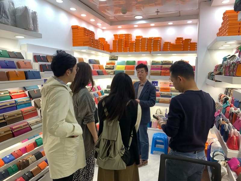 広州の革小物問屋で参加者へ商品を説明する佐藤大介