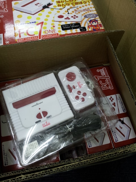 段ボール箱に収められた自社OEMのゲーム互換機と商品パッケージ