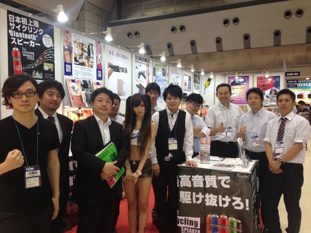 OEM商品が並ぶ共同出展ブースの前に立つ参加者たち