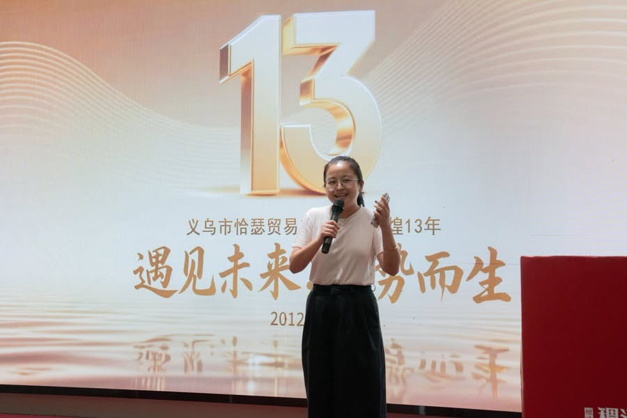 イーウーパスポート13周年の会場でマイクを持って話す女性マネージャー